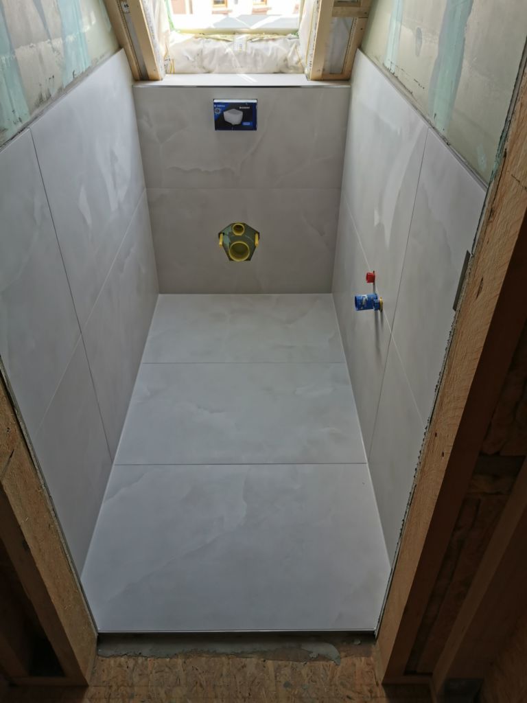 Raumansicht der Gäste Toilette mit Wand- und Bodenfliesen,