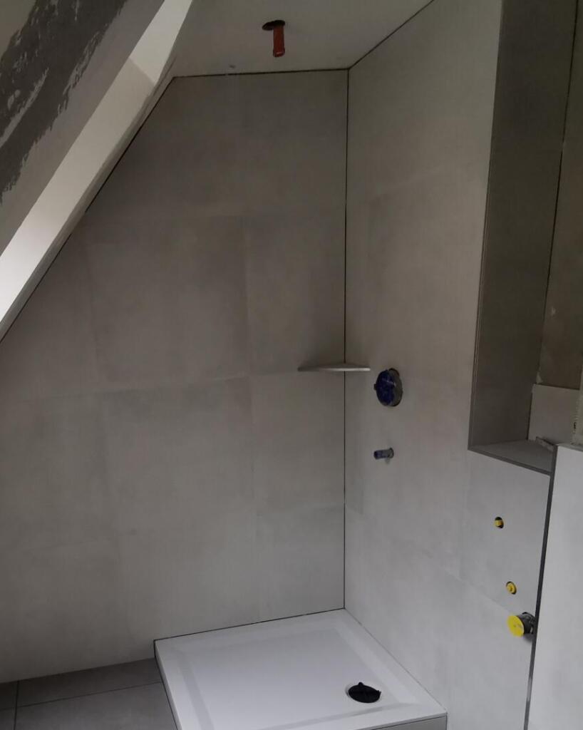 Unfertige Dusche unter Dachschräge mit grauen Wandfliesen