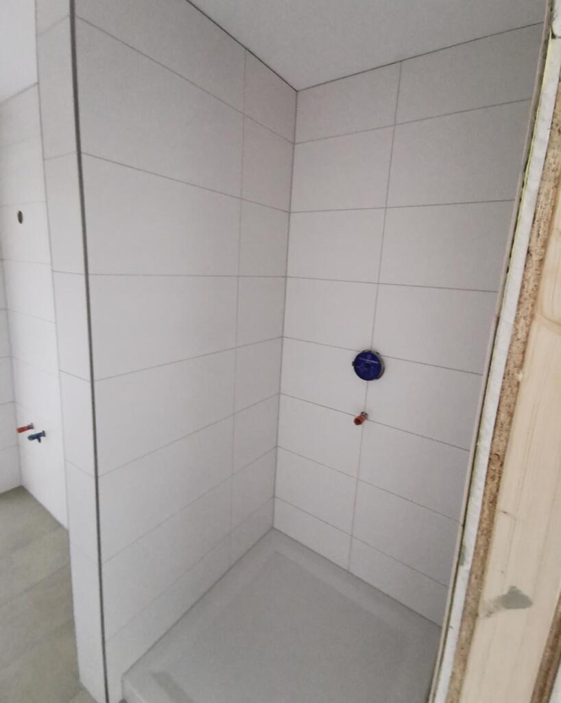 Neu geflieste Dusche im Rohbau mit Wasseranschlüssen