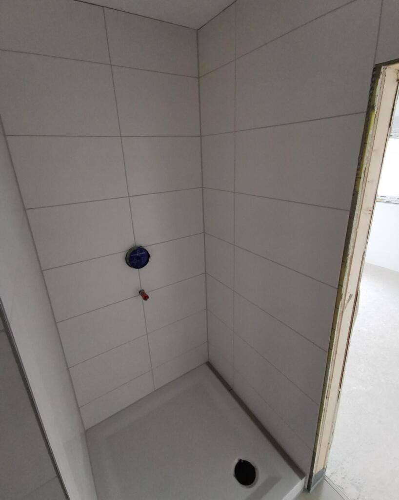 Geflieste Duschkabine im Rohbau mit Bodenablauf und Armaturanschlüssen